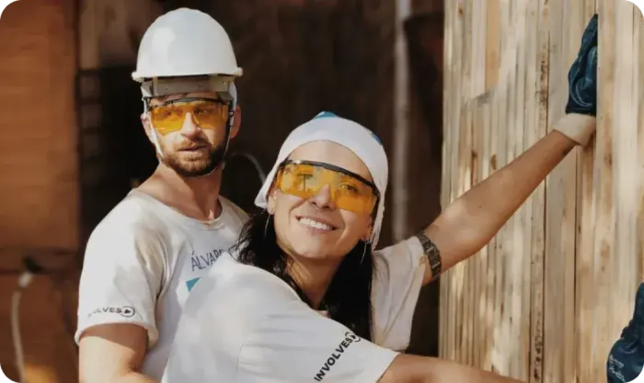 Two individuals wearing safety glasses and hard hats, demonstrating safety precautions in a work environment.