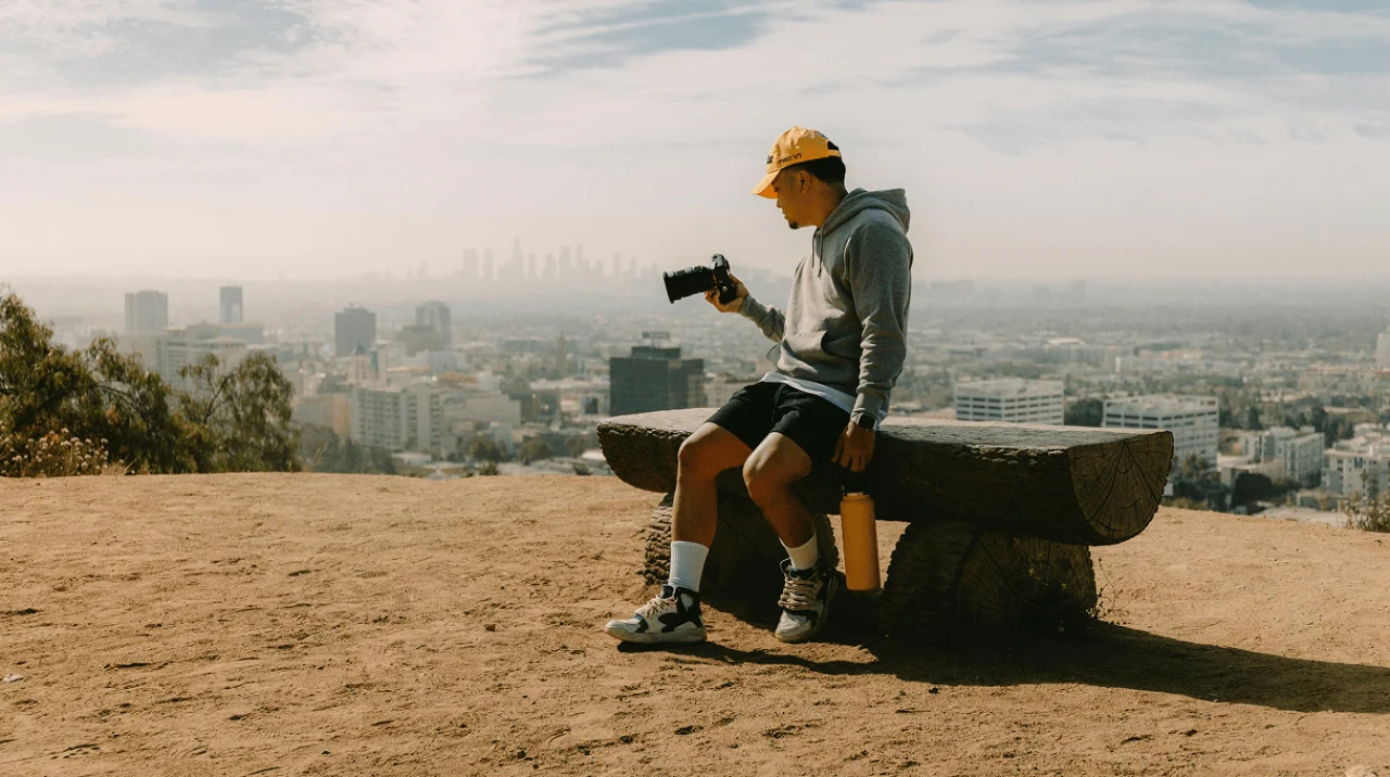 Solo founder planning a business strategy on a laptop, with a whiteboard of goals in the background