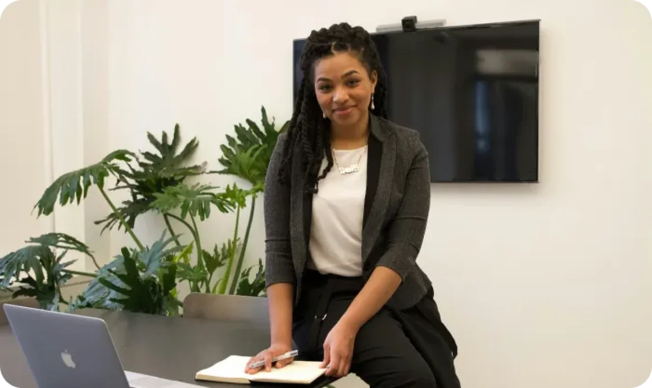 A woman smiling holding a pen and some papers.