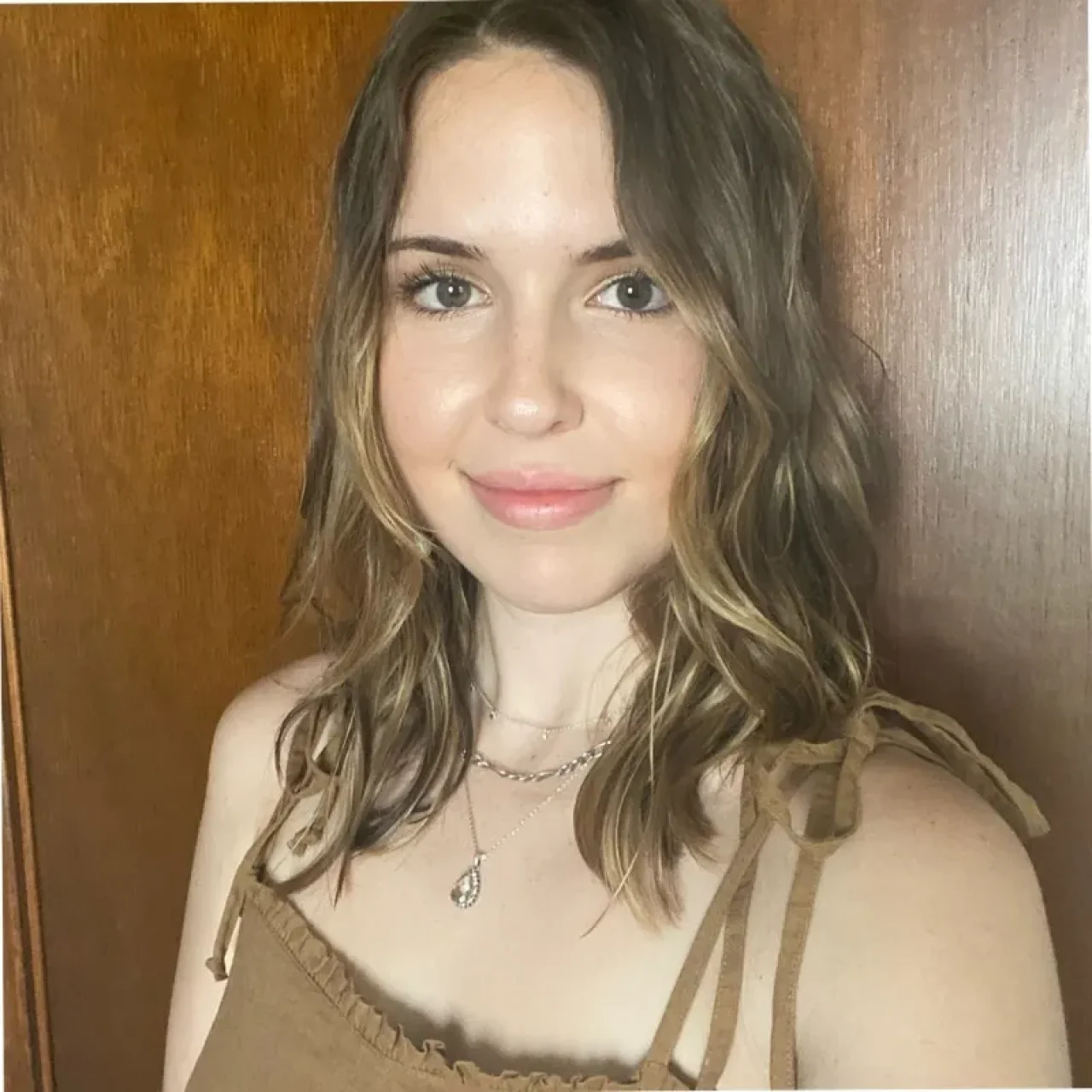 Sarah Hollenbeck, smiling, wearing professional attire, with a plain background