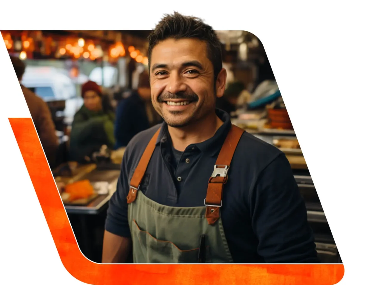 Smiling restaurant owner wearing an apron, standing in a busy kitchen with staff and warm lights in the background