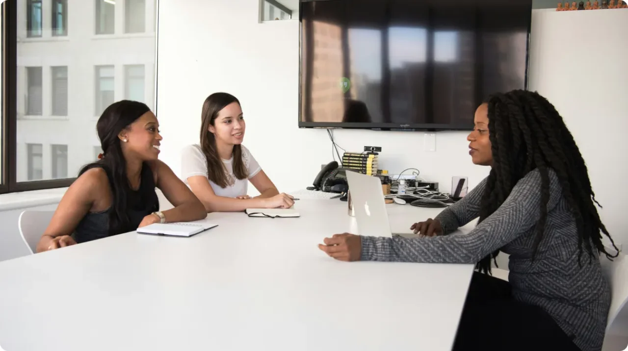 Three businesswomen having a team meeting and discussion in a modern office conference room.